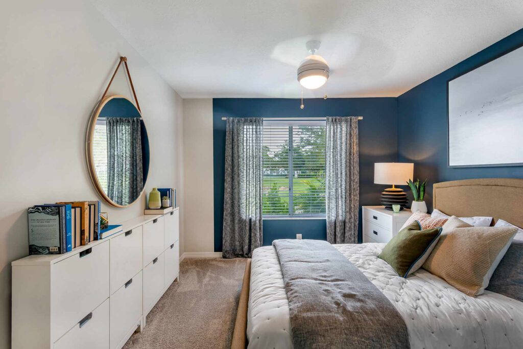 Model bedroom with large windows and blue accent wall